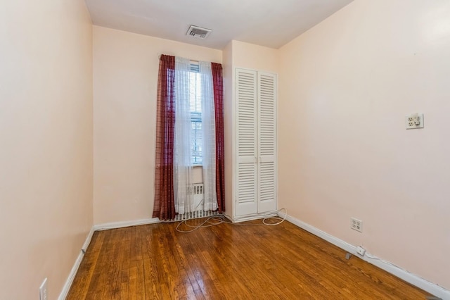 unfurnished room featuring hardwood / wood-style floors, baseboards, and visible vents