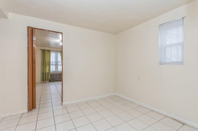 unfurnished room with light tile patterned floors, radiator heating unit, and baseboards
