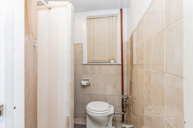 bathroom with toilet and tile walls