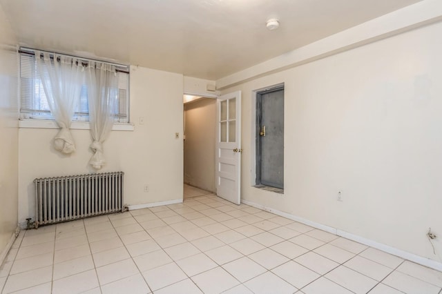 empty room with radiator heating unit, light tile patterned floors, and baseboards