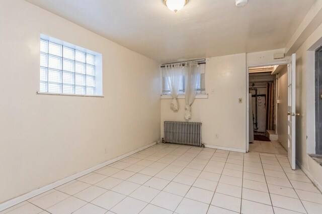 unfurnished room featuring baseboards, radiator, and light tile patterned flooring