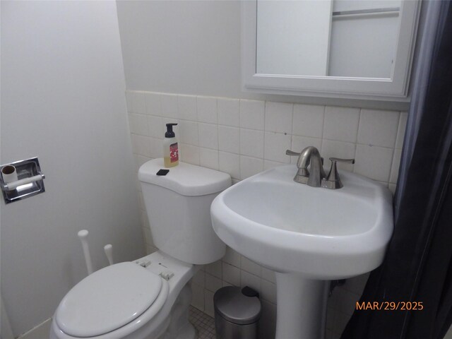 bathroom featuring toilet and tile walls