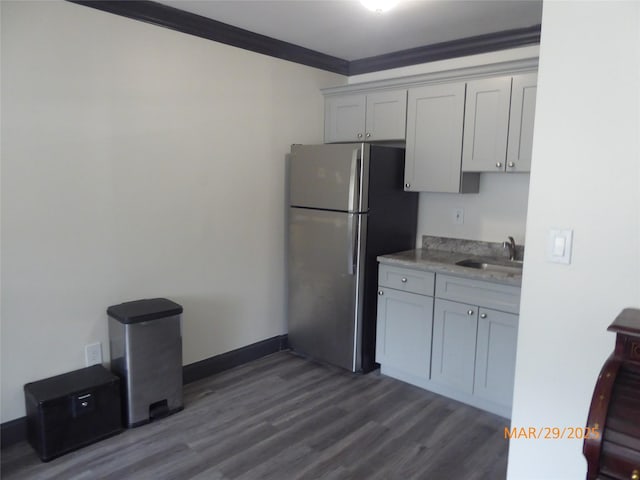 kitchen with a sink, ornamental molding, freestanding refrigerator, gray cabinetry, and dark wood-type flooring