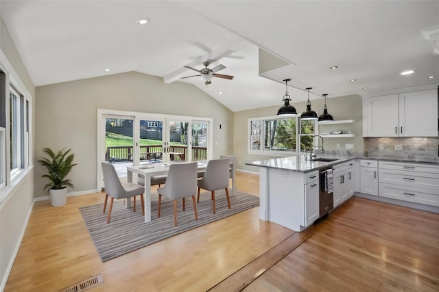 kitchen featuring a peninsula, white cabinetry, open shelves, and a sink