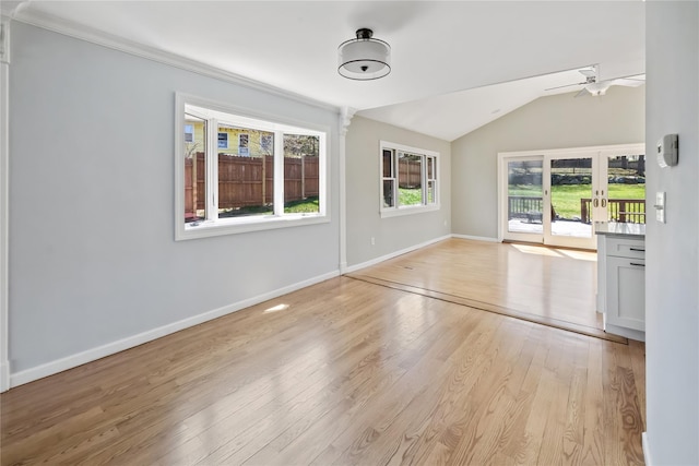unfurnished living room with light wood-type flooring, vaulted ceiling, baseboards, and ceiling fan