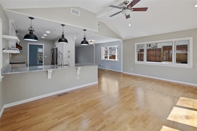 unfurnished living room with vaulted ceiling, visible vents, a sink, and ceiling fan