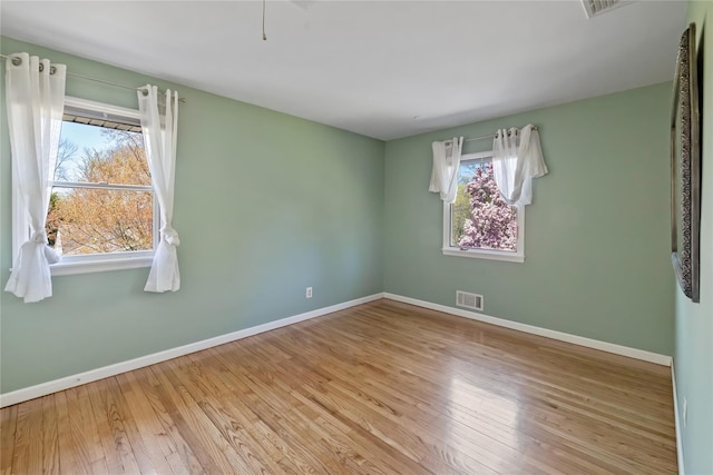 empty room featuring visible vents, baseboards, and wood finished floors