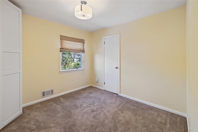 spare room with carpet floors, visible vents, and baseboards
