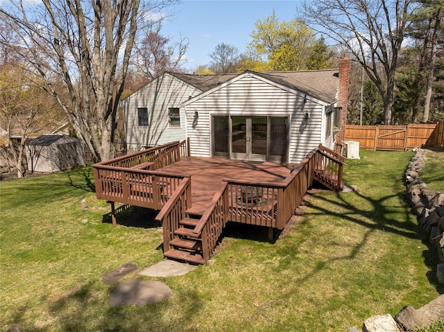 rear view of property featuring a chimney, a wooden deck, fence, and a yard