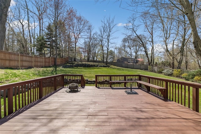 wooden terrace featuring a lawn, a fenced backyard, and an outdoor fire pit