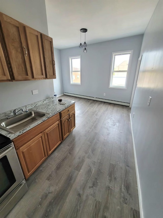 kitchen featuring a sink, a baseboard heating unit, stove, and brown cabinets
