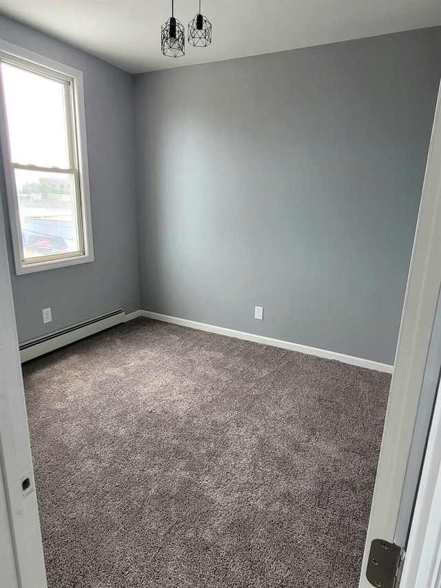 spare room featuring carpet, a baseboard heating unit, and baseboards