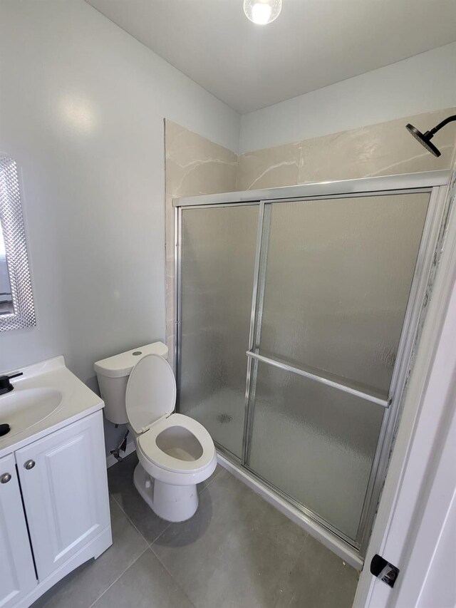 full bathroom featuring a shower stall, vanity, tile patterned flooring, and toilet