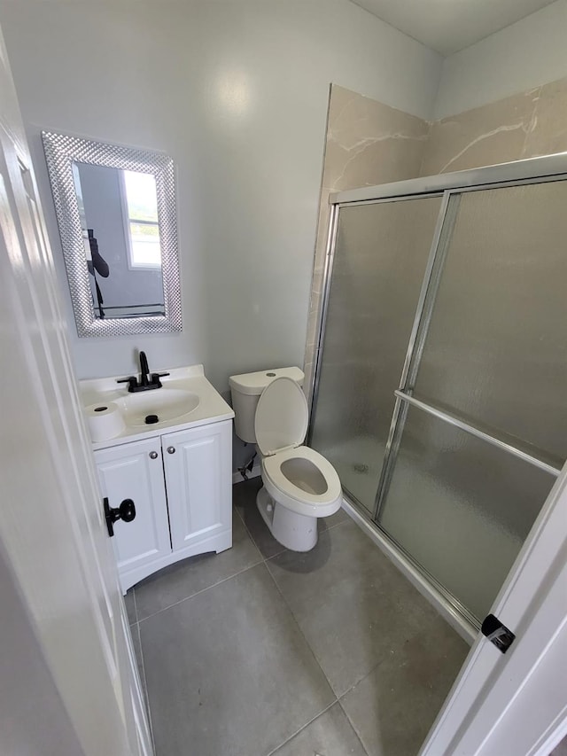 full bath with toilet, a stall shower, vanity, and tile patterned floors