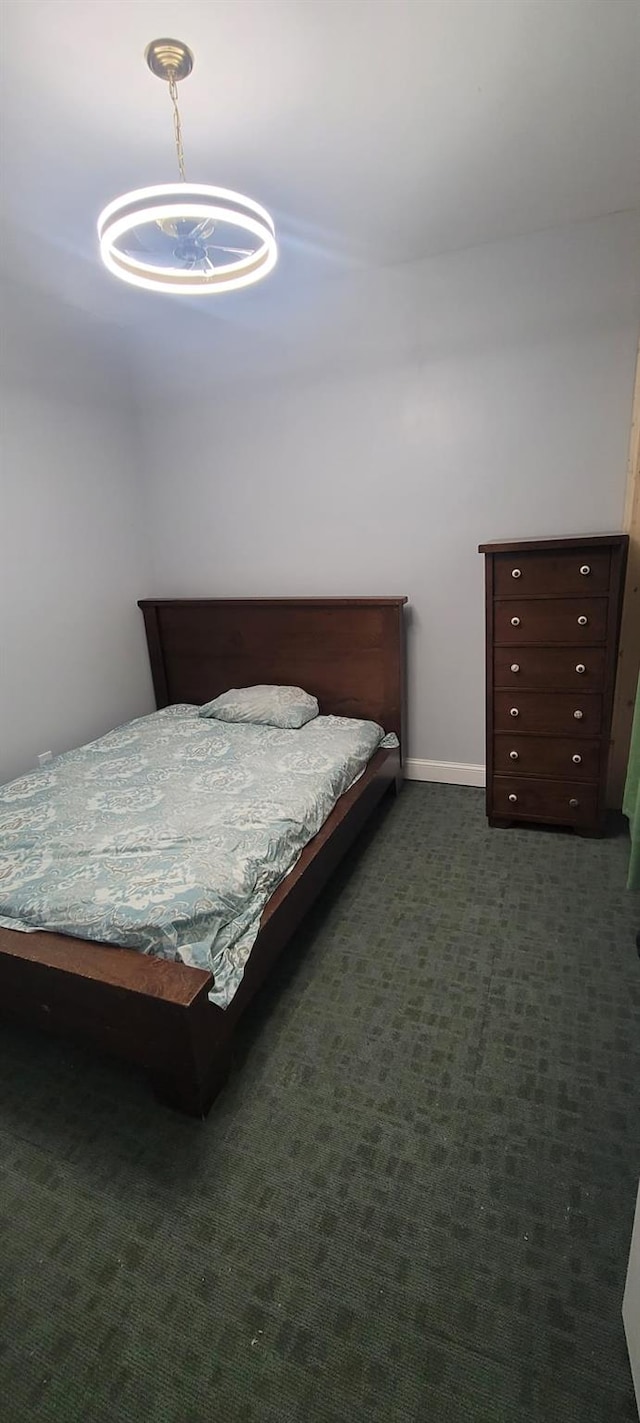 bedroom featuring baseboards and dark carpet