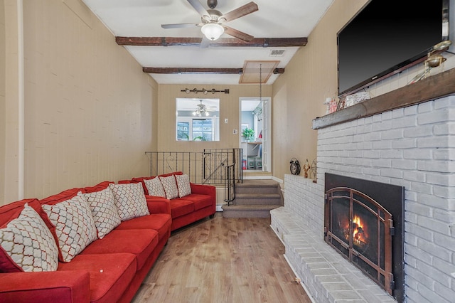 living area featuring wood finished floors, ceiling fan, beamed ceiling, and visible vents