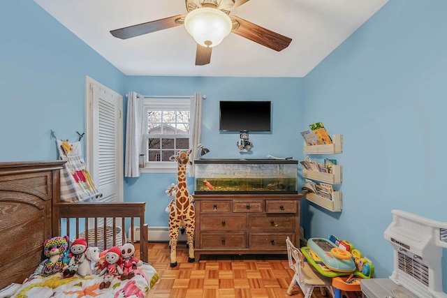 bedroom with a ceiling fan and a baseboard heating unit