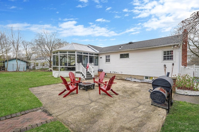 back of house featuring a patio, a sunroom, an outdoor fire pit, a yard, and fence