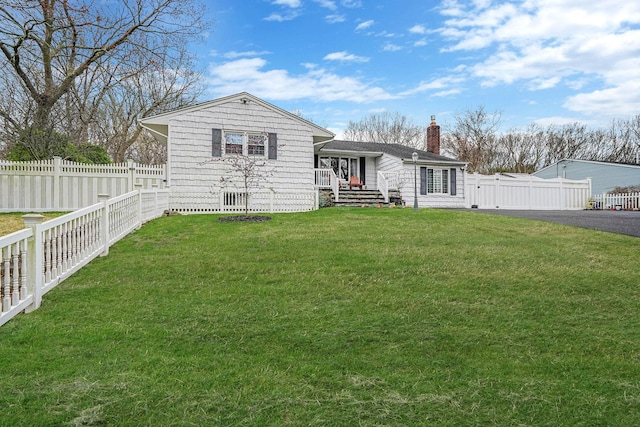 view of front of house featuring a front lawn, fence private yard, and a chimney