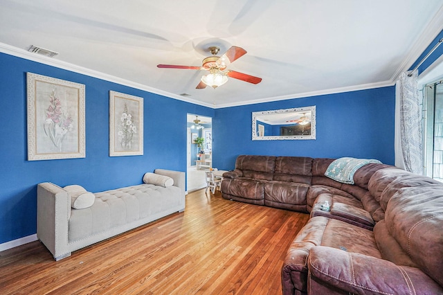 living area with crown molding, a ceiling fan, visible vents, and wood-type flooring