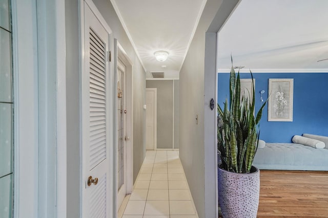 corridor featuring baseboards, visible vents, and light tile patterned floors