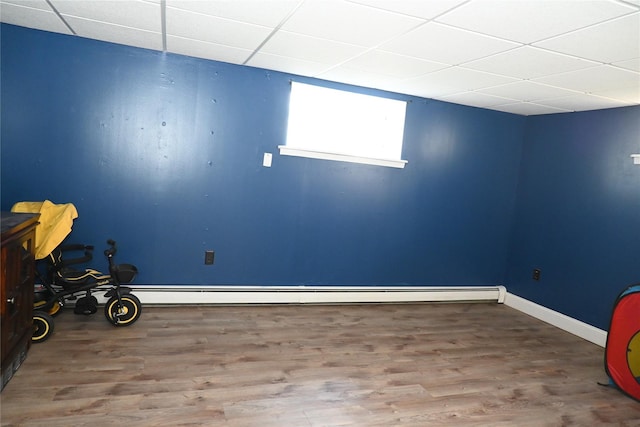 interior space featuring wood finished floors, a drop ceiling, and baseboards