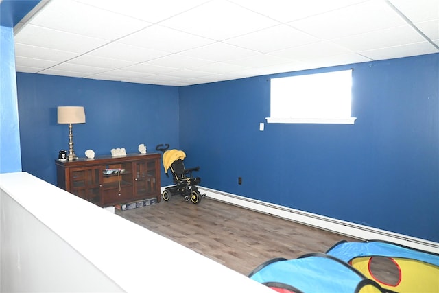 bedroom with wood finished floors, a drop ceiling, and baseboards