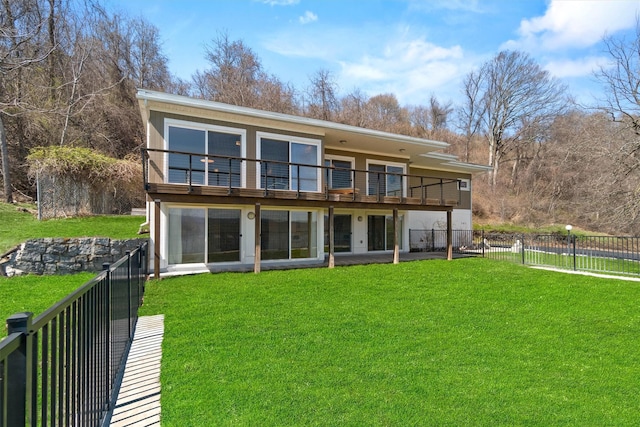 back of property featuring a yard, a balcony, and a fenced backyard