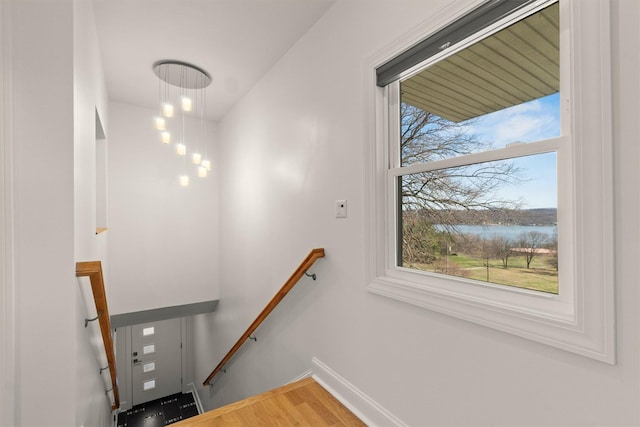 staircase with a water view, baseboards, and wood finished floors