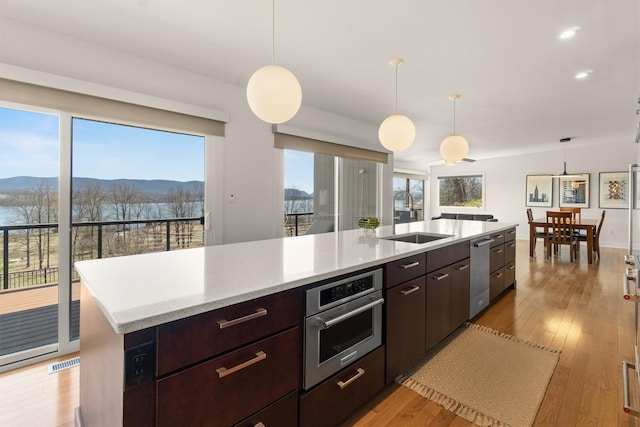 kitchen with a mountain view, light wood-style flooring, visible vents, oven, and a sink