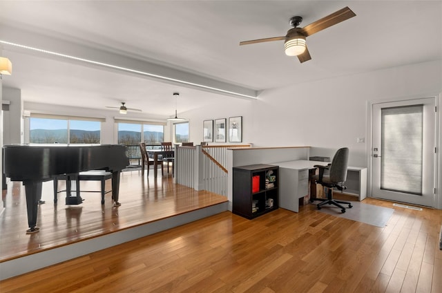 office space with beamed ceiling, a ceiling fan, and wood finished floors