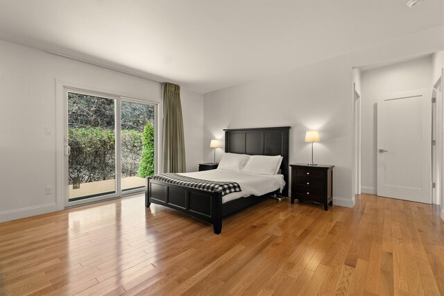 bedroom with access to exterior, light wood finished floors, and baseboards