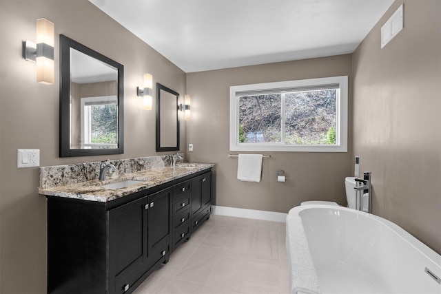 bathroom featuring visible vents, double vanity, a freestanding tub, and a sink