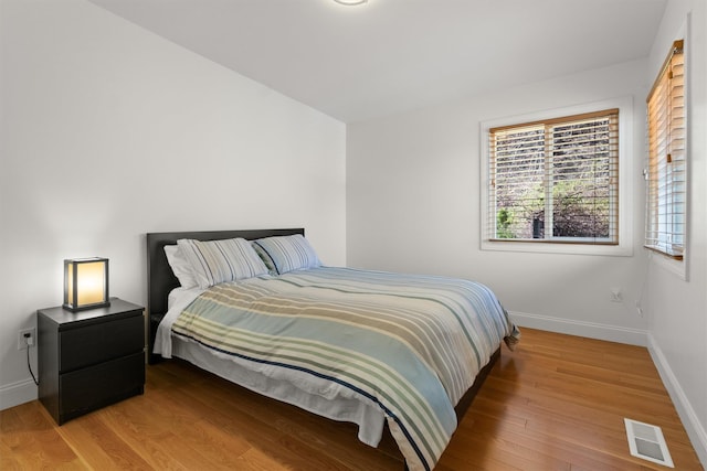 bedroom featuring light wood finished floors, visible vents, and baseboards