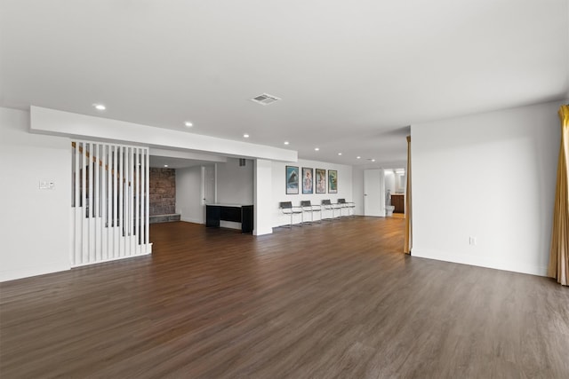 unfurnished living room with bar, visible vents, recessed lighting, dark wood-style flooring, and baseboards