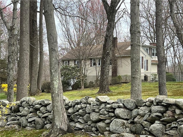 view of side of property with a chimney and a lawn