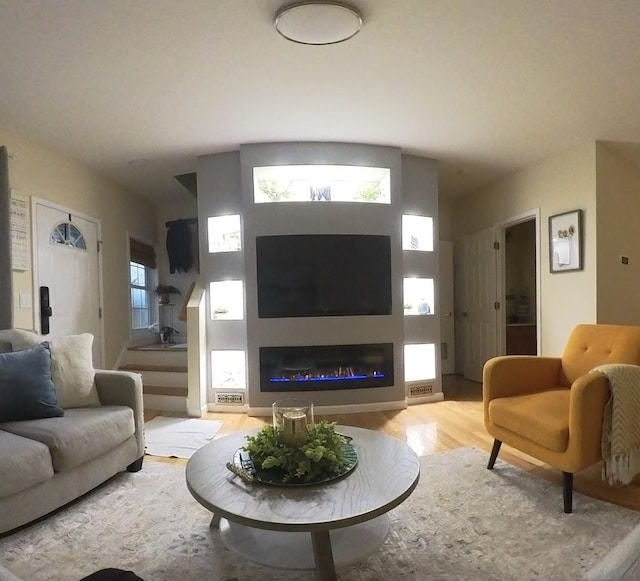living area with wood finished floors and a glass covered fireplace