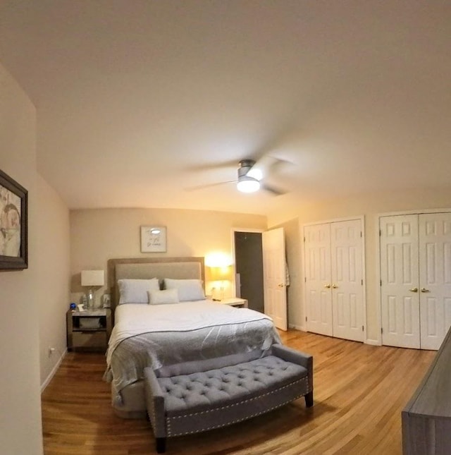 bedroom with light wood-style floors, baseboards, multiple closets, and a ceiling fan