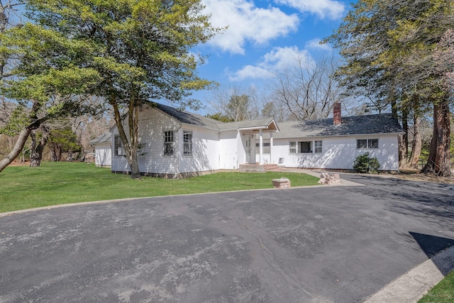 single story home with a chimney and a front lawn