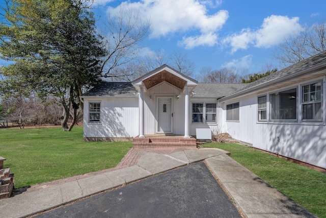 ranch-style house with a front lawn and roof with shingles