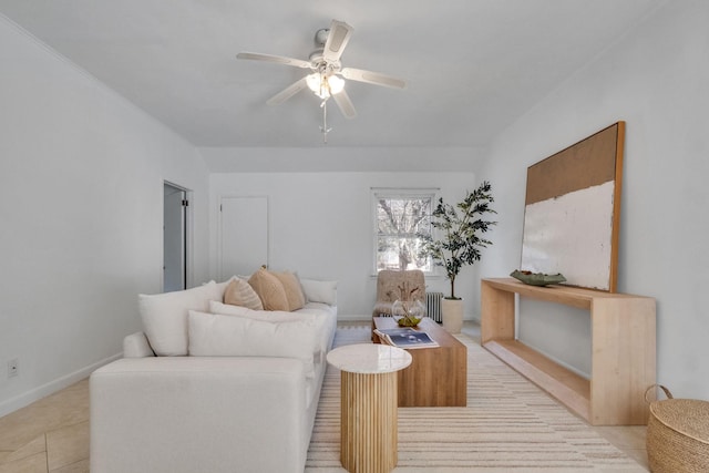 living room featuring radiator heating unit, light tile patterned floors, baseboards, and ceiling fan