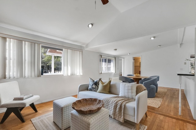 living area featuring baseboards, light wood-style floors, ceiling fan, and vaulted ceiling