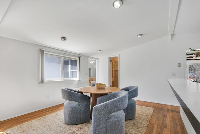 dining area featuring baseboards, wood finished floors, and lofted ceiling with beams