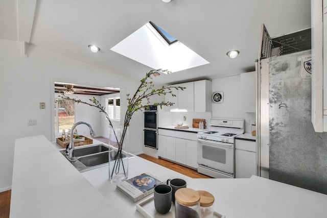 kitchen featuring gas range gas stove, white cabinets, multiple ovens, visible vents, and a sink