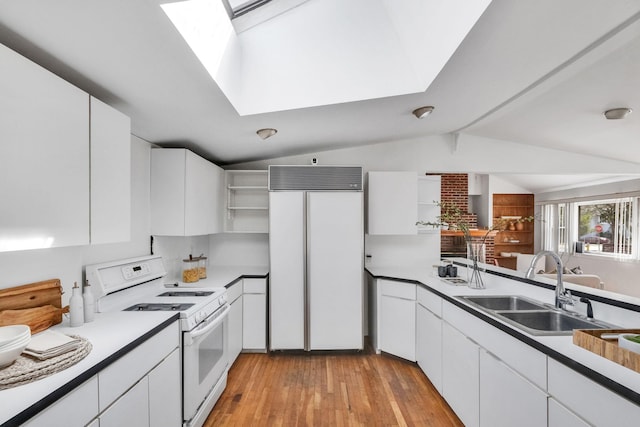 kitchen with white gas stove, built in fridge, open shelves, lofted ceiling with skylight, and a sink