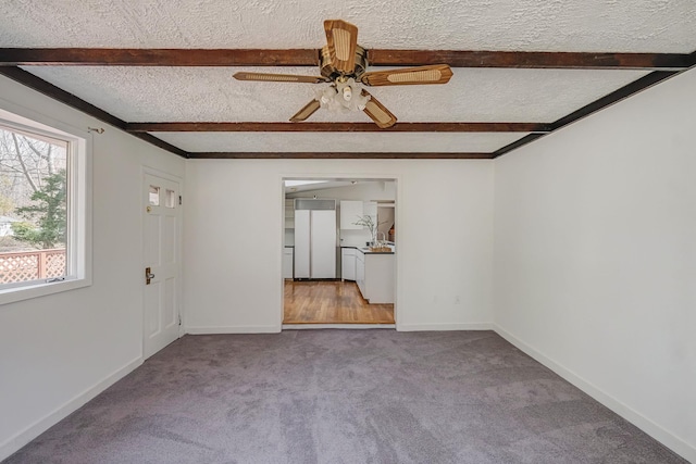 unfurnished living room with carpet floors, beamed ceiling, and a textured ceiling