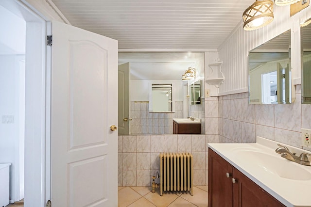 bathroom with tile walls, radiator, tile patterned flooring, and vanity