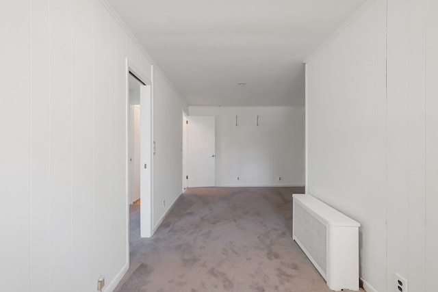 hallway featuring radiator heating unit, light colored carpet, and baseboards