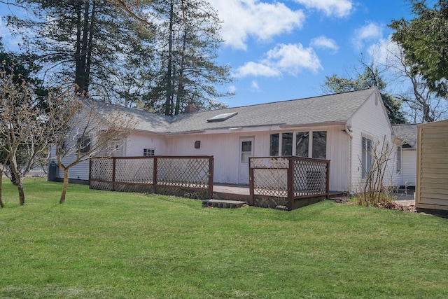rear view of house featuring a yard, a wooden deck, and a shingled roof