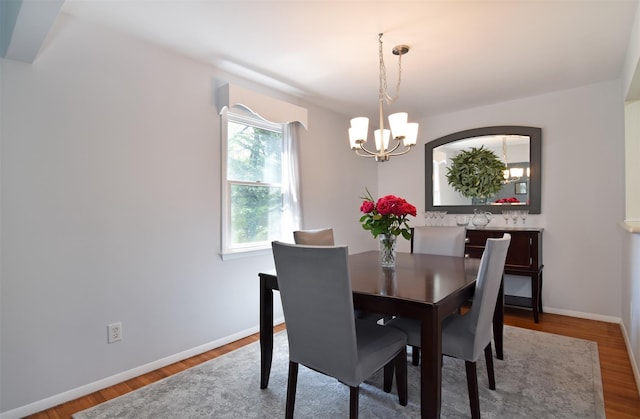 dining space with a notable chandelier, wood finished floors, and baseboards
